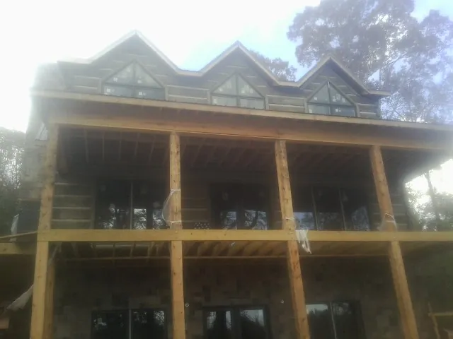 Dormers and porch framing on a large log home under construction — Roof Coating work by our crew in Addison
