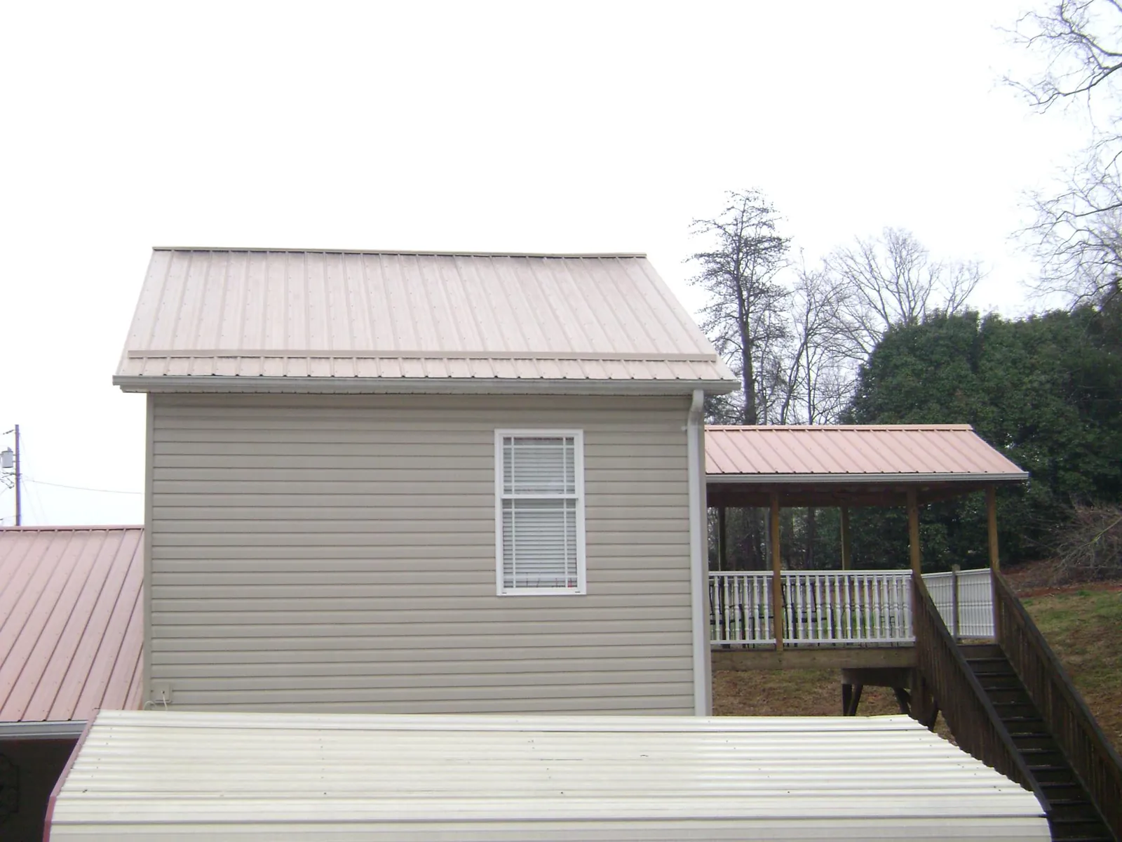 Tan metal roofs on a two story addition and attached porch, from a Roof Replacement job in Addison
